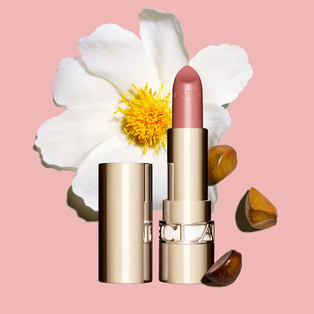 Joli Rouge Lippenstift von Clarins vor einer Kamelienblüte auf weißem Hintergrund